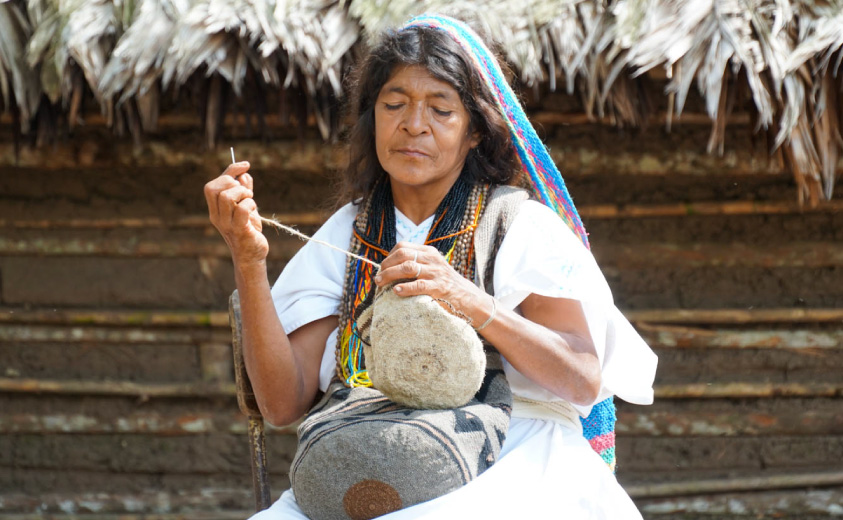 Foto de artesana del Pueblo Arhuaco tejiendo una mochila